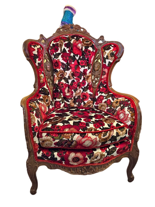 beautiful reupholstered wingback chair with ornate wood carvings of cherubs
